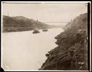 Vy över två båtar i Panamakanalen under dess konstruktion med en hängbro bortom, 1913 (silvergelatintryck)